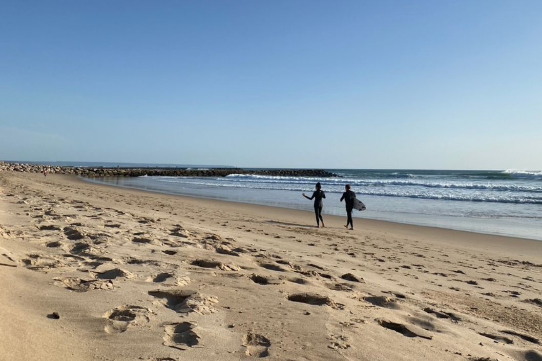 two surfers walking on the beach in Costa da Caparica in March