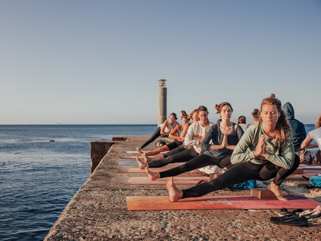 people striking a yoga pose right near the water's edge